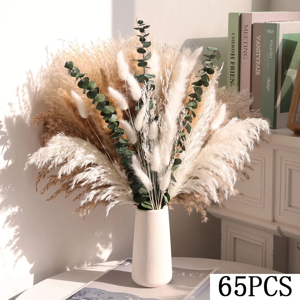 White vase with dried pampas grass and eucalyptus on a table with books in the background