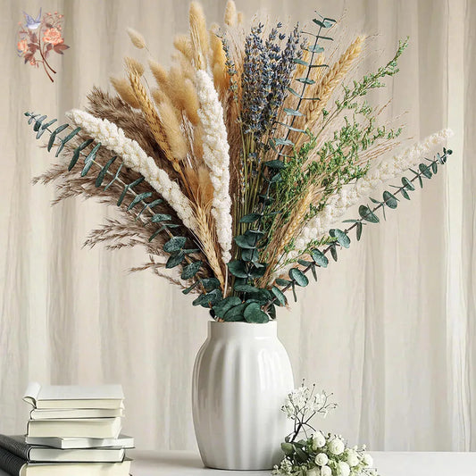 Decorative bouquet of dried pampas grass, eucalyptus, and preserved flowers arranged in a white ceramic vase against a soft neutral background.