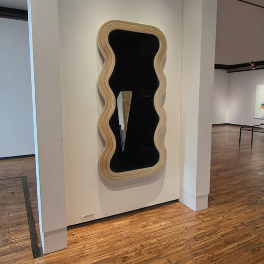 Natural wavy wooden wall mirror with irregular scalloped frame mounted on an indoor wall