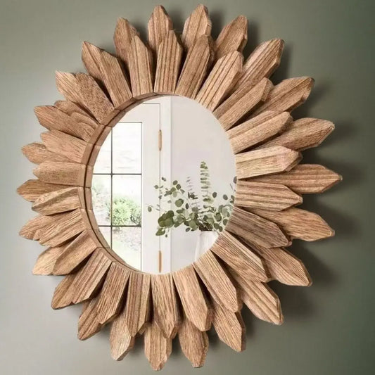 Round wooden sunflower wall mirror with layered petal design, displayed on a green accent wall in a bright, natural interior.